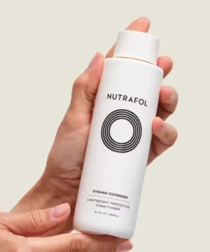 Nutrafol Strand Defender Conditioner bottle on model's hand